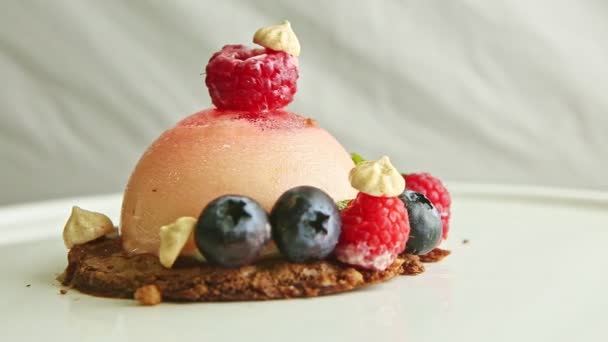 Närbild rosa glasyr dessert trendigt dekorerad med bär roterar på plattan — Stockvideo