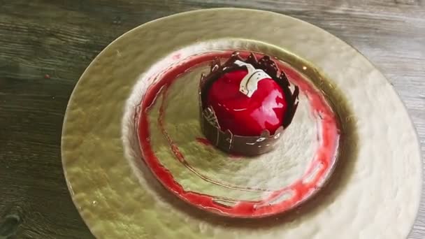 Original dessert with red glaze and castle shape chocolate rotates on golden plate — Stock Video