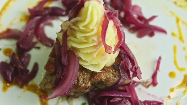 Close-up panorama bij gebakken stukjes vlees met aardappelpuree en rode ui — Stockvideo