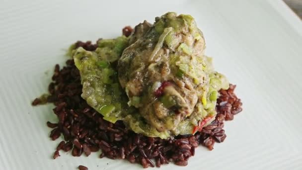 Closeup zoom out from baked quail with onion sauce on wild rice rotates on plate — Stock Video