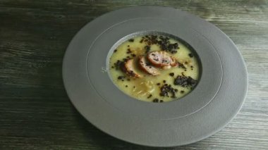 İnsan eli, sosis dilimleriyle süslenmiş soğan kremalı çorba ile kalın tabağı döndürür.