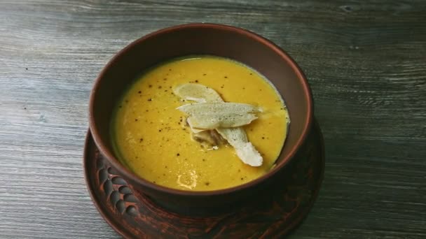 Зум из желтого кремового супа, украшенный грибами и сушеным хлебом — стоковое видео
