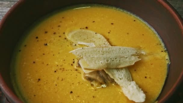 Arriba macro vista de la sopa de crema amarilla decorada con setas y pan seco — Vídeos de Stock