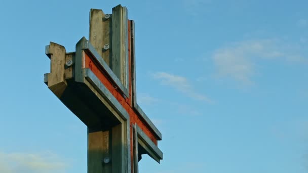 Detailní velký kovový kříž stojí proti modré obloze s bílými plovoucími mraky — Stock video
