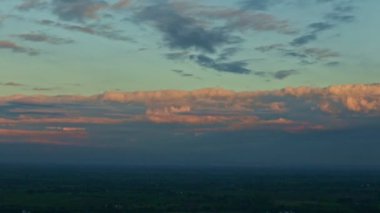 Gün batımında mavi gökyüzünde pofuduk pembe bulutlar ile tropikal manzaraya yavaş bir manzara bırakılır.