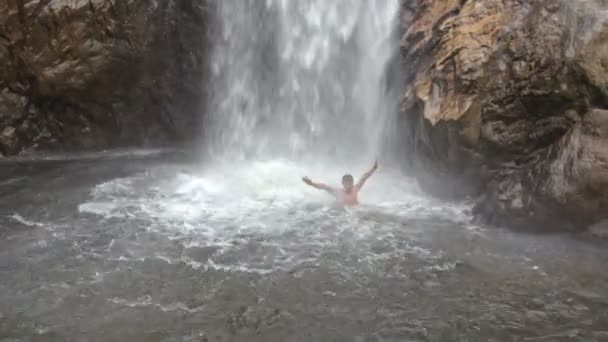 Guy Swims up to High Waterfall Foamy Splashes among Rocks — Stock Video