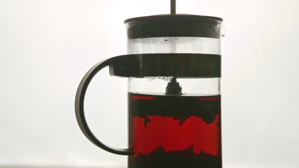 Closeup glass teapot with green tea rotates on pedestal against white — ストック動画