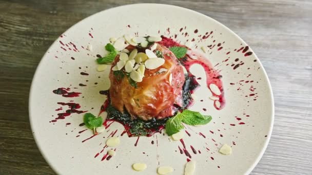 Trendy decorated baked apple with syrup and nuts rotates on plate — Stockvideo