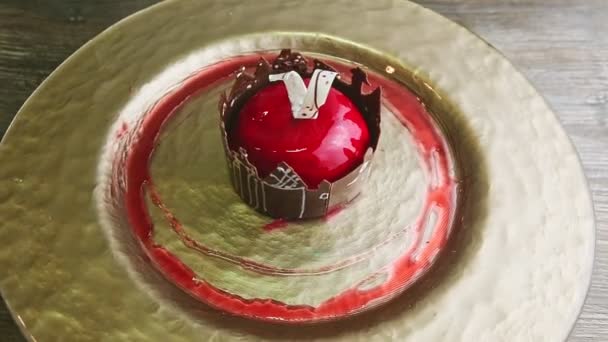 Slow zoom in at red glazed dessert with castle shape chocolate rotates on golden plate — ストック動画