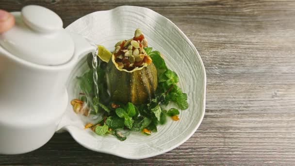 Human hand pours hot water form white kettle in original plate with pumpkin dessert — Stock Video