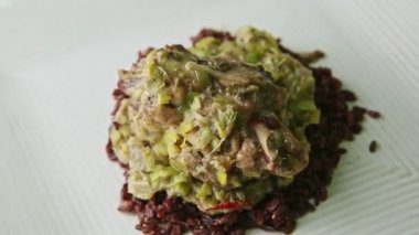 closeup fried partridge with green onion dressing on wild rice rotates on plate