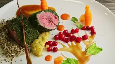 closeup human hand rotate finely decorated restaurant meat dish on wooden table