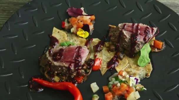 Closeup zoom in at fried meat pieces with potato chips and vegetable salad on black — Stockvideo