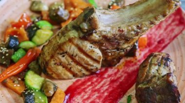 zoom out from gilled rib with big pieces of meat and fried vegetables on pink plate
