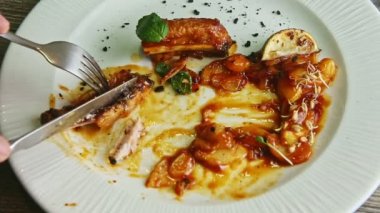 İnsan eli, ızgara et kaburgalarını çatal ve bıçakla kahverengi sosla keser.