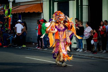 Concepcion De La Vega, DOMINICAN REPUBLIC - FEBRUARY 09, 2020: dominican man in pied carnival costume walks by city street full of people on February 9 in Concepcion De La Vega