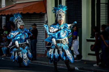 Concepcion De La Vega, DOMINICAN REPUBLIC - FEBRUARY 09, 2020: native people in pied blue costumes pass by city street at dominican carnival on February 9 in Concepcion De La Vega
