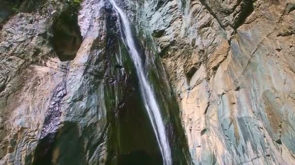 Panorama arriba en la cascada de montaña fuerte larga en altos acantilados de piedra oscura — Vídeo de stock