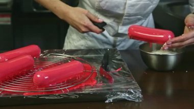 Şef üniformalı yakın plan kadın modern restoran mutfağındaki hindistan cevizi parçacıklarıyla pembe kremalı pasta süsler.