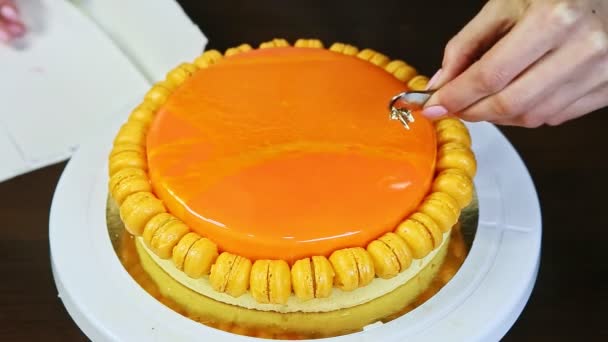 Confectioner decorate with edible gold leaf orange glazed round sponge cake — Stock video