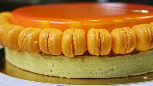 Panorama de primer plano en todo naranja esmaltado pastel de esponja decorado con macarrones — Vídeo de stock