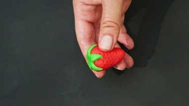 top view closeup woman hands make red strawberry shaped marzipan candy