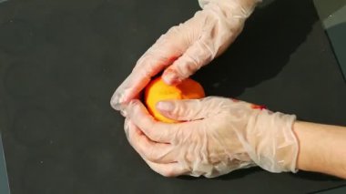 Ellerindeki üst görünüm, küçük turuncu badem ezmesi kütleli bir toptan oluşan eldiven şeklinde.