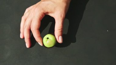 İnsan elinin üst görüntüsü küçük yeşil elma şekilli badem ezmesi şekeri gösteriyor.
