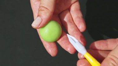 Üst kattaki yakın plan eller küçük yeşil badem ezmesinden elma şekilli şekerler.