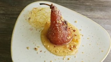 Karamel tabakta dönerek güzelce dekore edilmiş fırınlanmış armudu yakınlaştır.