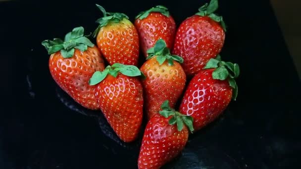 Vue du haut mise au point du groupe de fraises rouges mûres entières sur la surface noire — Video