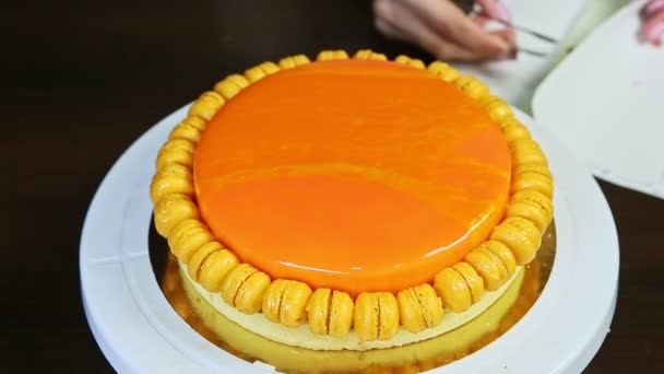 Preparation to decorate by edible gold leaf orange glazed round cheesecake — Stock Video