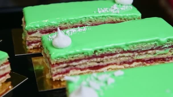 Panorama zbliżeniowa na zielone szyby warstwowe porcje ciasta serwowane na złotych stojakach — Wideo stockowe