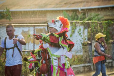 Concepcion De La Vega, DOMINICAN REUBLIC - 11 Şubat 2019: Concepcion De La Vega 'da 11 Şubat' ta Dominik Karnavalı 'nda parlayan palyaço kostümlü adam tropikal yağmurun altında geçti.