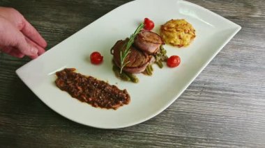 İnsan eli, orijinal beyaz restoran tabağını fırında etle çevirir.