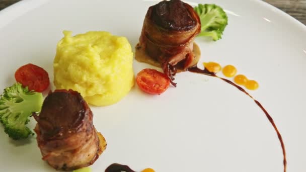 Closeup finely decorated meat pieces fried in bacon with puree and broccoli — Stock Video