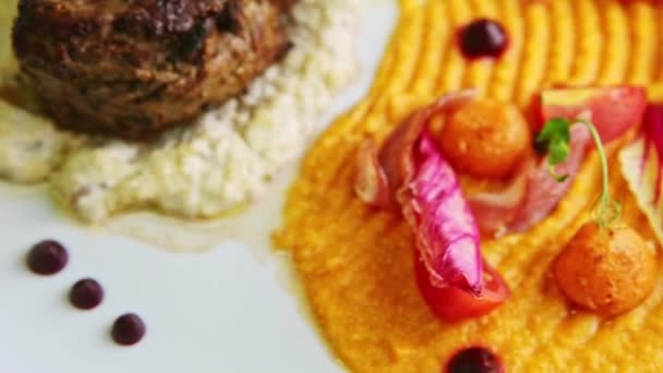 Крупный план большой кусок жареного мяса с модным украшенным гарниром вращается на тарелке — стоковое видео