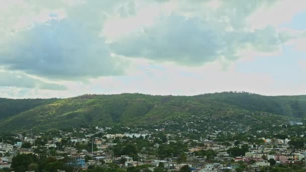 Lentamente panorama en la pequeña ciudad contra montañas verdes y nubes esponjosas — Vídeos de Stock