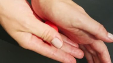 Kadın elinin üst görüntüsü kırmızı badem ezmesi parçasından çilek şekli alır.