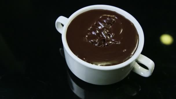 Enfoque fuera de la taza redonda blanca grande llena de chocolate negro derretido — Vídeo de stock