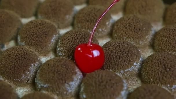 Macro view op originele vorm oppervlak van chocolade cake met enkele rode kers — Stockvideo
