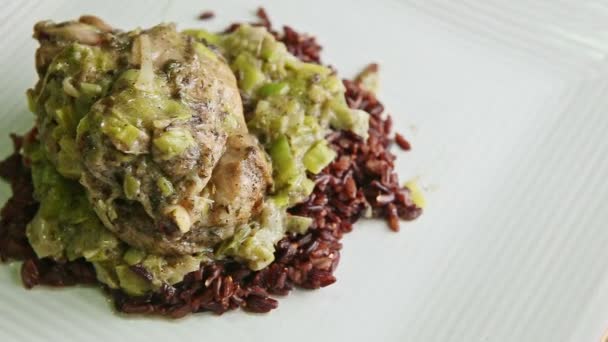 Top view closeup roasted quail with green onion dressing on wild rice rotates on plate — Stock Video
