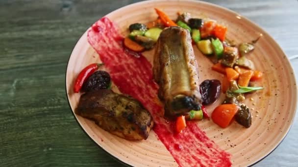 Rostade revben med stora bitar kött och grillade grönsaker roterar på rosa tallrik — Stockvideo