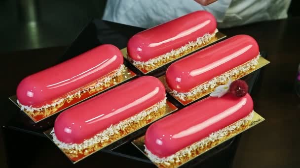 Process of decorating by big ripe raspberry pink glazed oval eclairs by confectioner — Stock Video