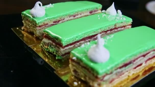 Plateau noir gros plan avec trois portions de gâteau émaillé vert tourne autour — Video