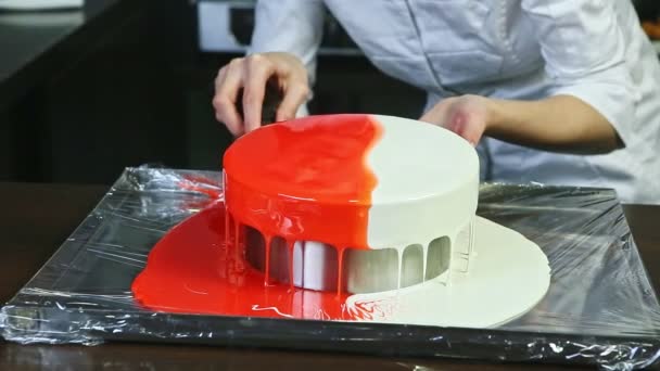 Pasticciere cerca di prendere pesante rosso e bianco glassato intera torta di formaggio rotondo — Video Stock