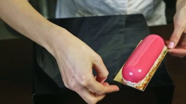 Şekerci pembe camlı oval ekinlerden birini hindistan cevizi talaşıyla süslüyor.