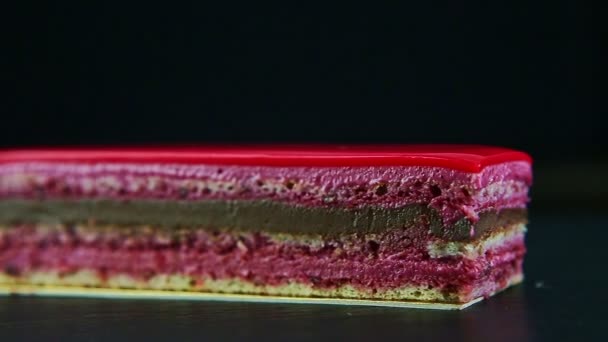 Langzaam panorama op een stuk roze geglazuurde chocolade en bessen gelaagde taart — Stockvideo