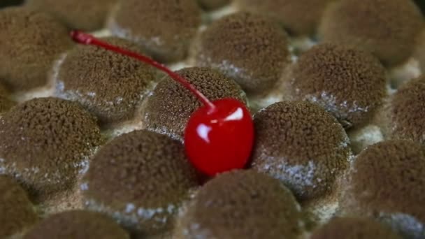 Macro view op trendy gevormde chocoladetaart oppervlak versierd met rode kers — Stockvideo