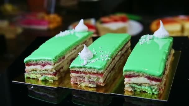 Porciones de pastel en capas acristaladas verdes con bizet blanco girando alrededor en soporte negro — Vídeos de Stock